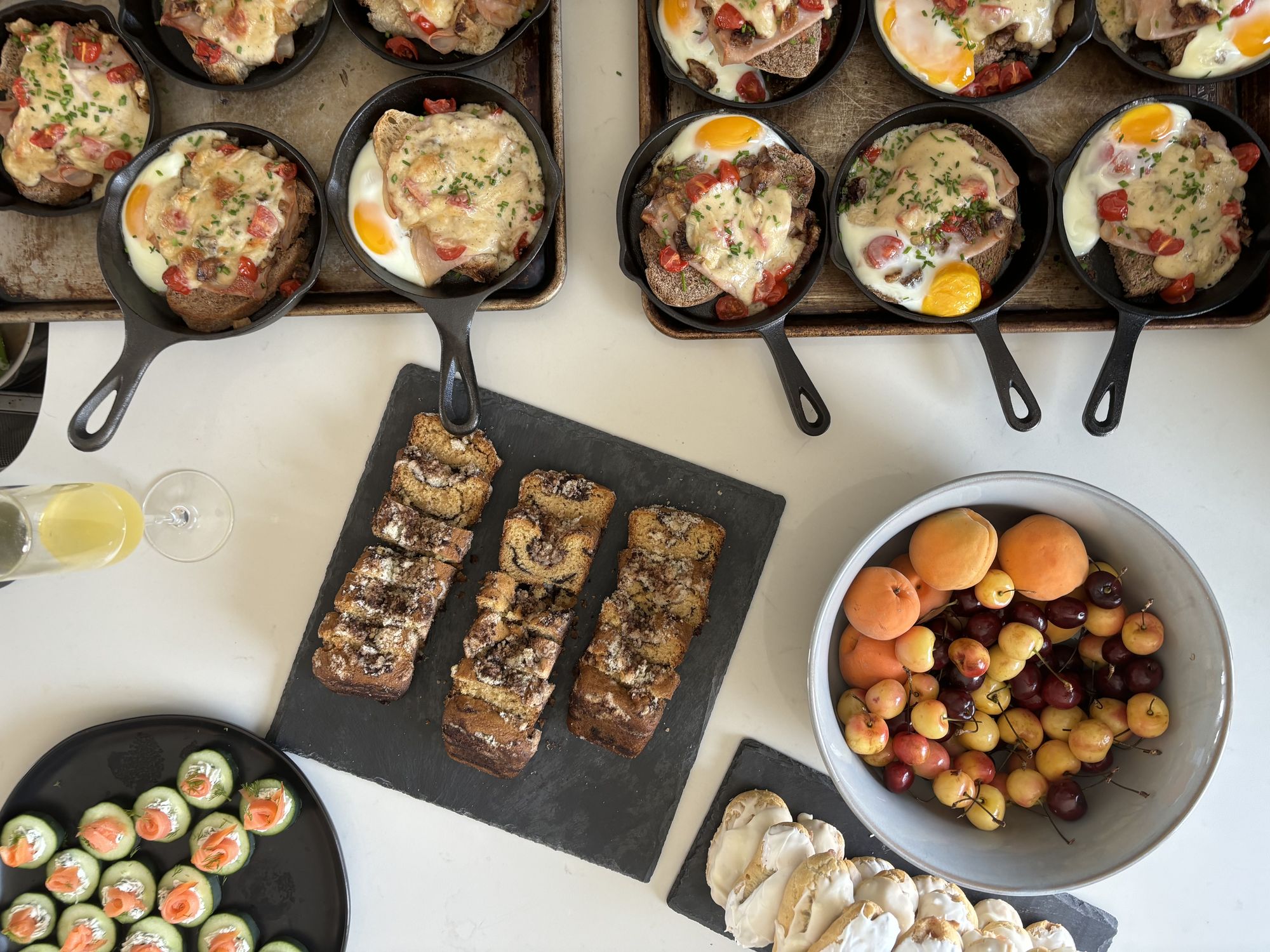 A July brunch spread, including a riff on Kentucky hot browns, fruit, coffee cakes, eclairs, and smoked salmon on cucumber.